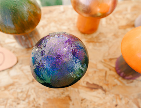 Overhead view of three painted concrete mushrooms from Ben's “Magick” series. 2023. Photo by Sarah Schmidt (https://www.sarahschmidtphoto.com/)